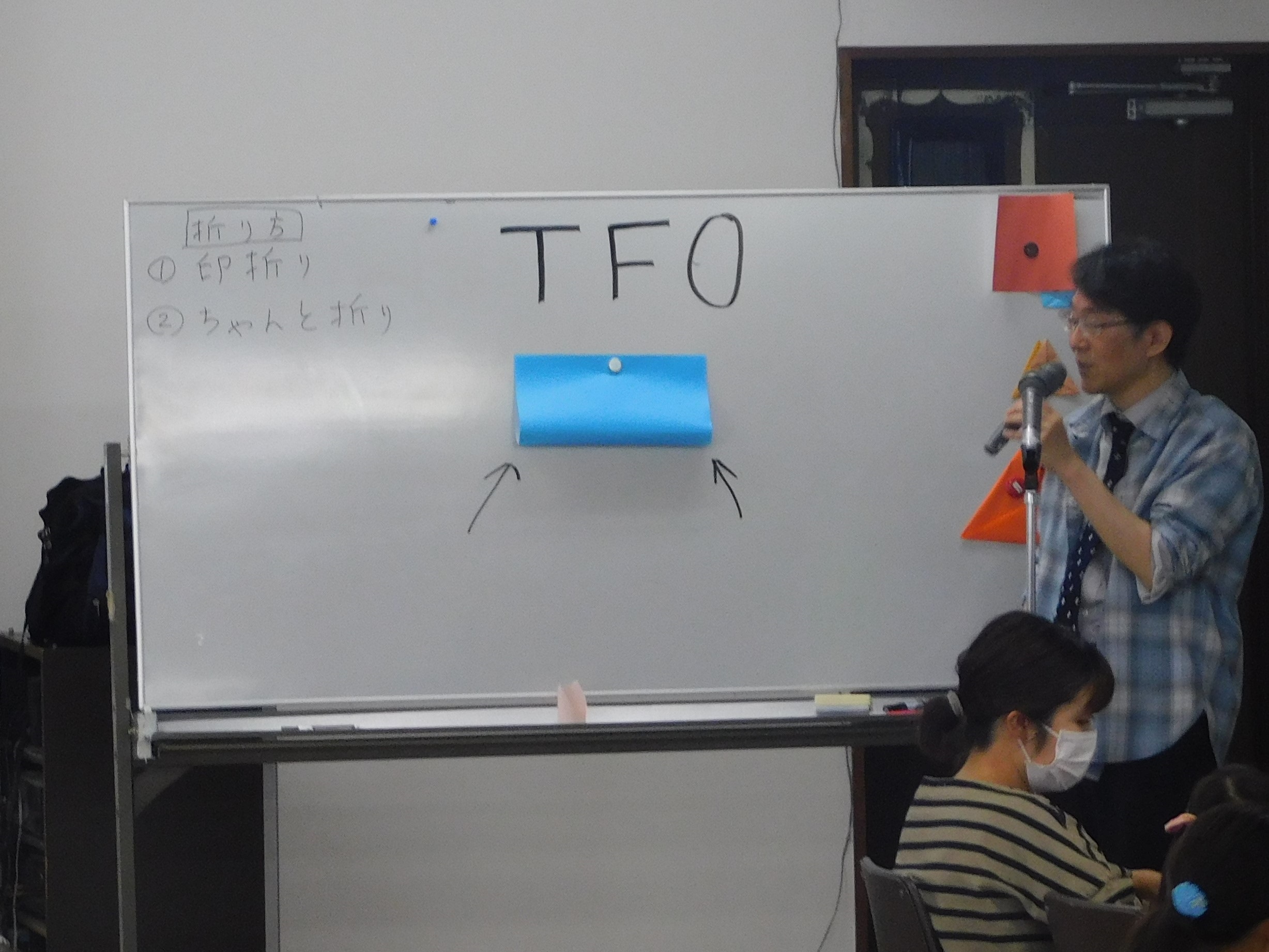 先生が謎の飛行物体TFOの折り方を説明しています